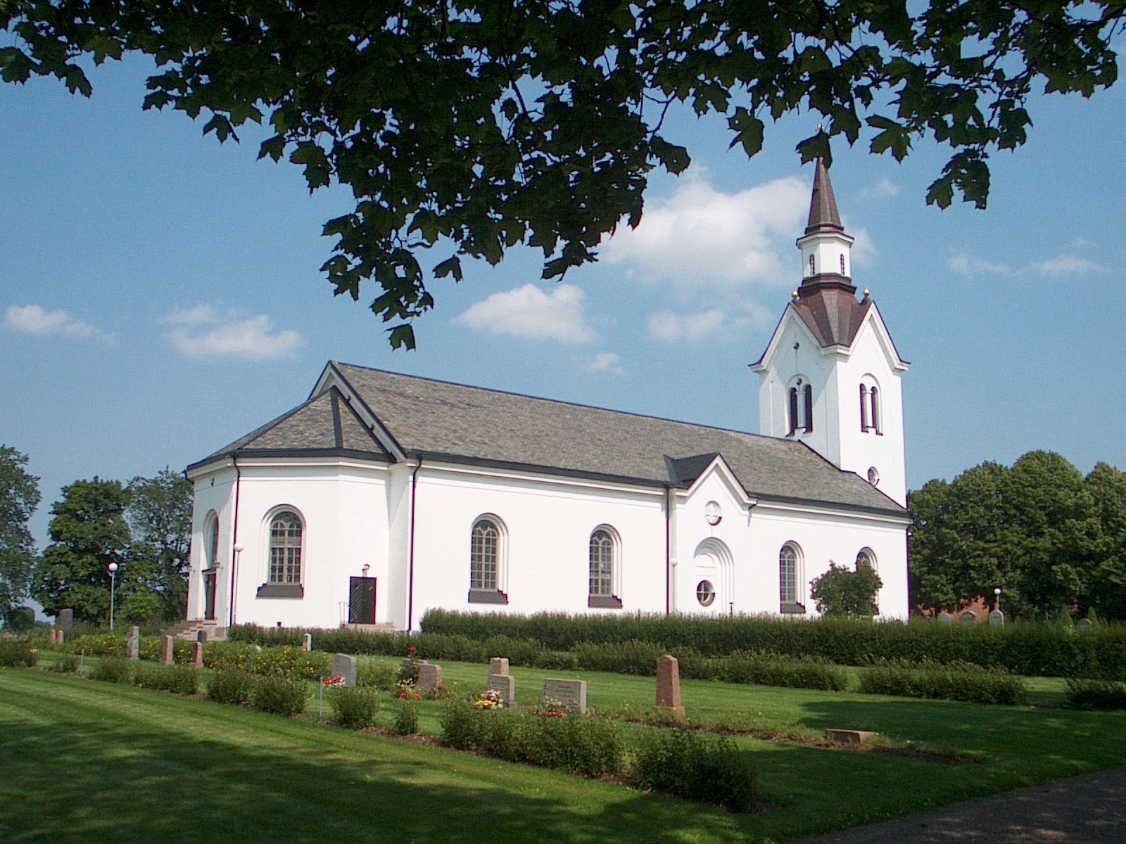 Högby kyrka med gravstenar i förgrunden.