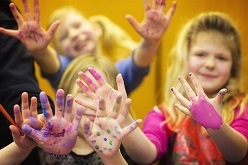 Barn som målat sina händer och sträcker fram dessa.