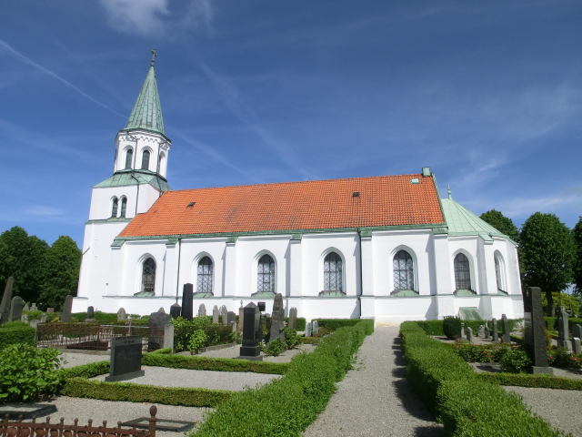 Vit kyrka med torn och rött tegeltak.