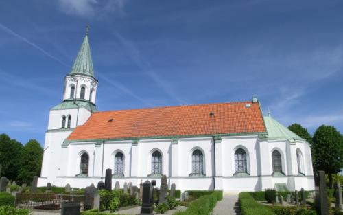 Vit kyrka med torn och rött tegeltak.