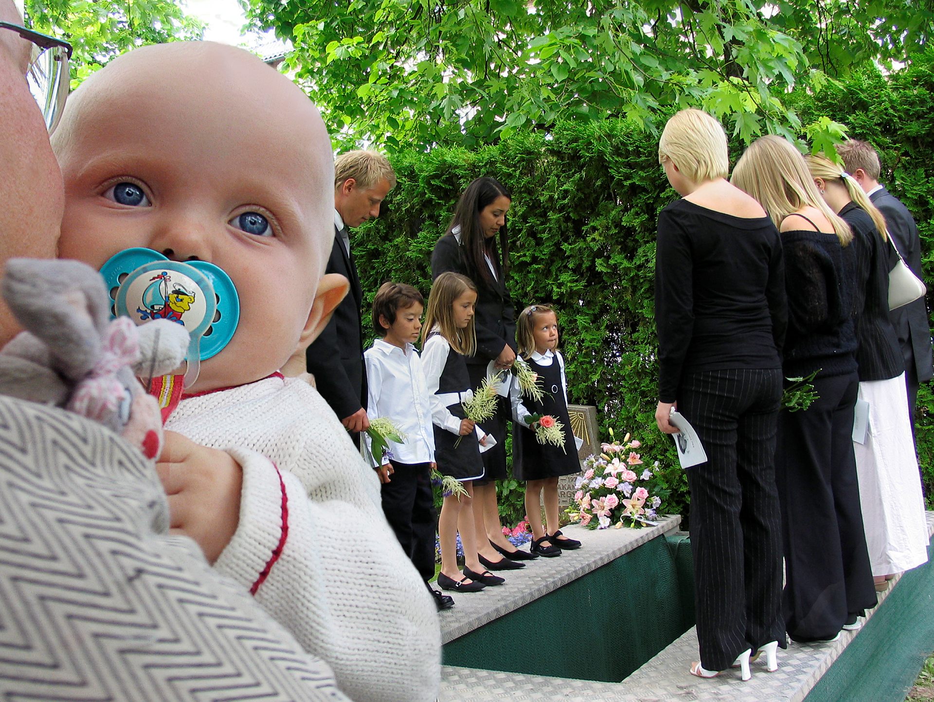 Människor tar avsked vid graven på kyrkogården efter gudstjänsten.
