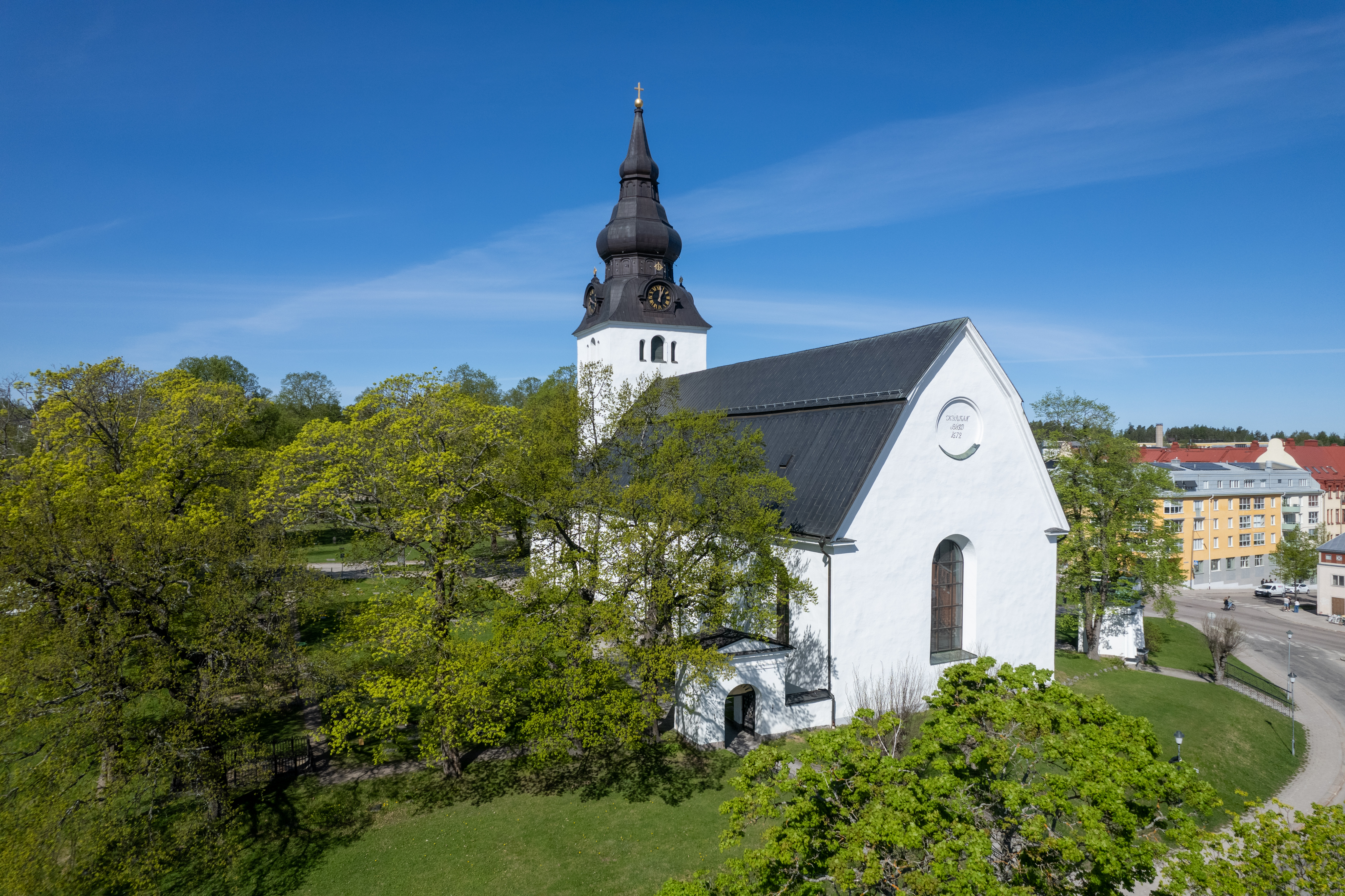 En drönarbild på Jakobs kyrka omgiven av gröna lövträd