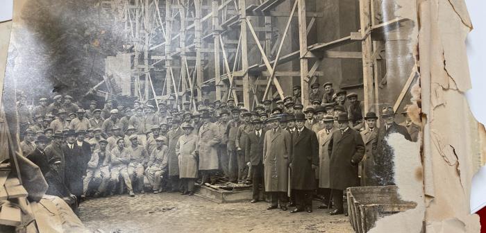 19 december 1934. Då var det klart med renoveringen av Storkyrkan.
Ute på gården samlas byggarna. Byggnadsställningar är av trä och det är väldigt många män som står uppradade på gården. Man ser tydligt vilka som är arbetare.
Ett plåtkuvert från svunna tider har nu hittas i en av urnorna.