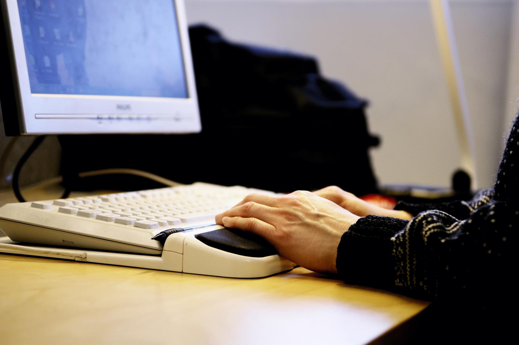 Närbild på händer som skriver på ett tangentbord. En bit av en skärm syns också.