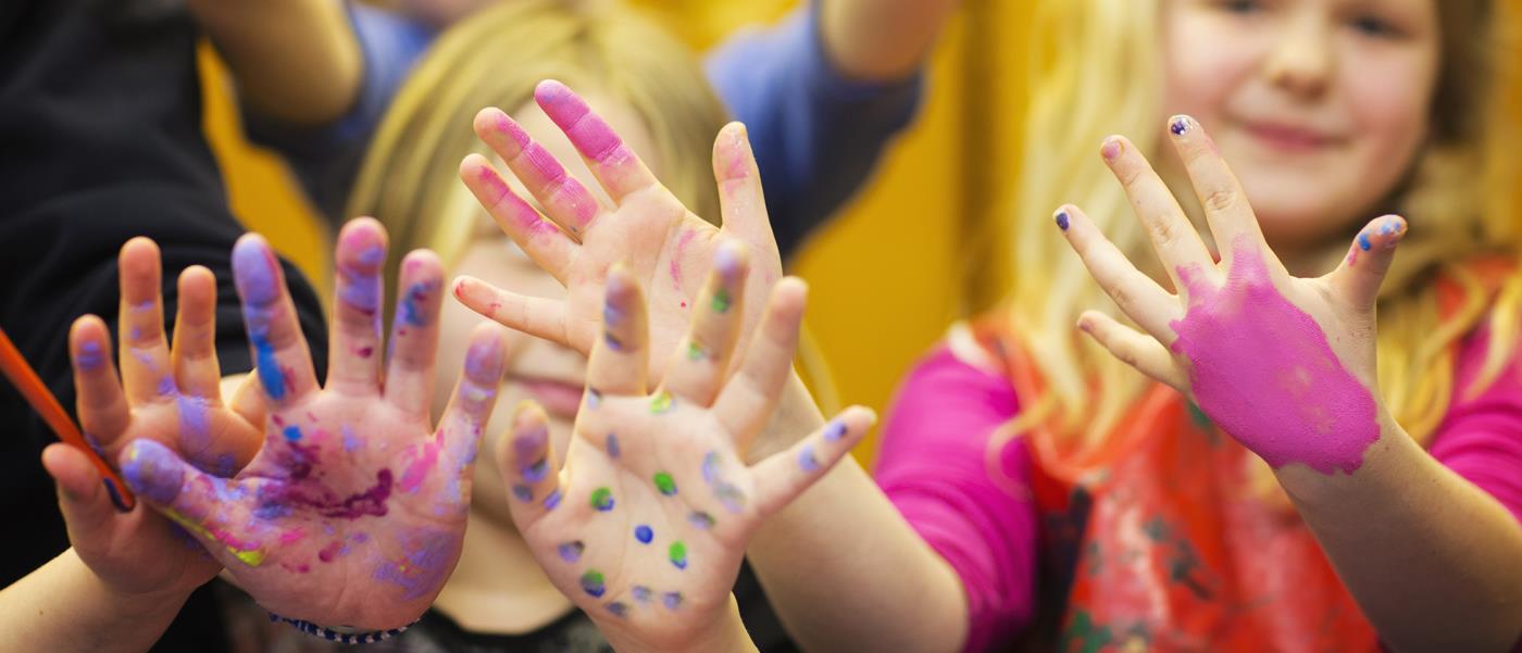 Glada barn med färgglada händer har riktigt roligt.
