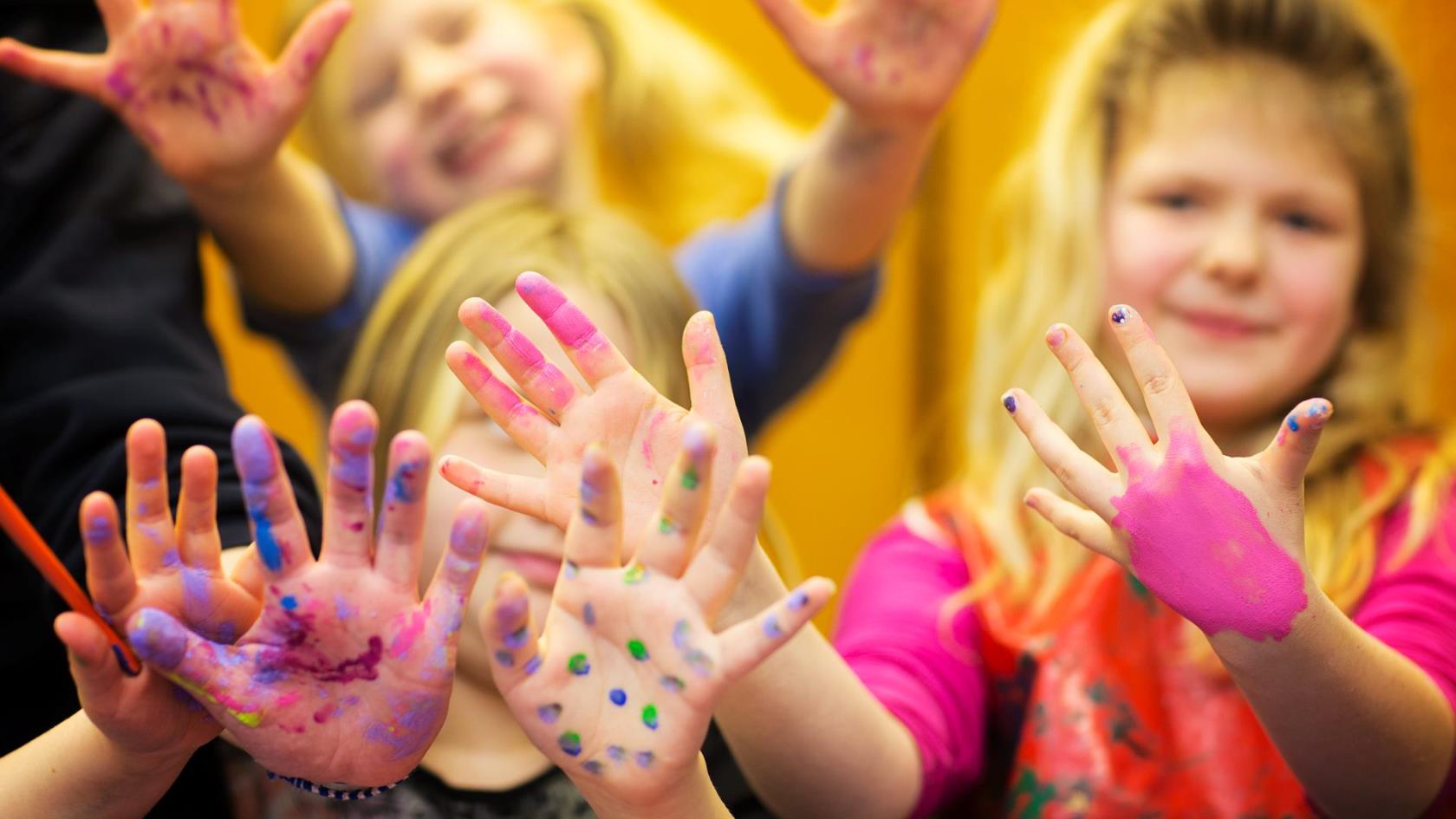 Glada barn sträcker fram sina färgkladdiga fingrar.