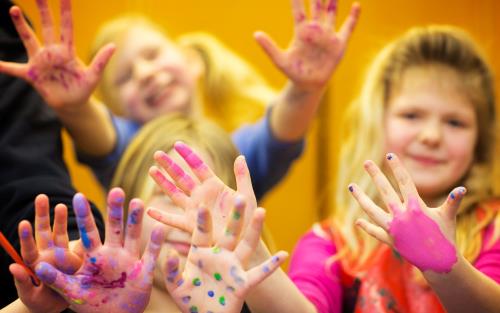 Glada barn sträcker fram sina färgkladdiga fingrar.