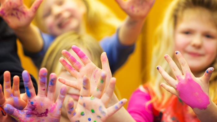 Glada barn sträcker fram händerna målade med fingerfärger
