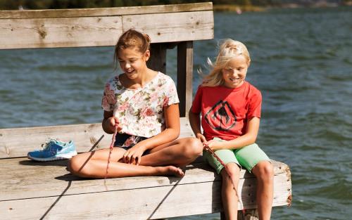 Två barn sitter på en brygga och fiskar