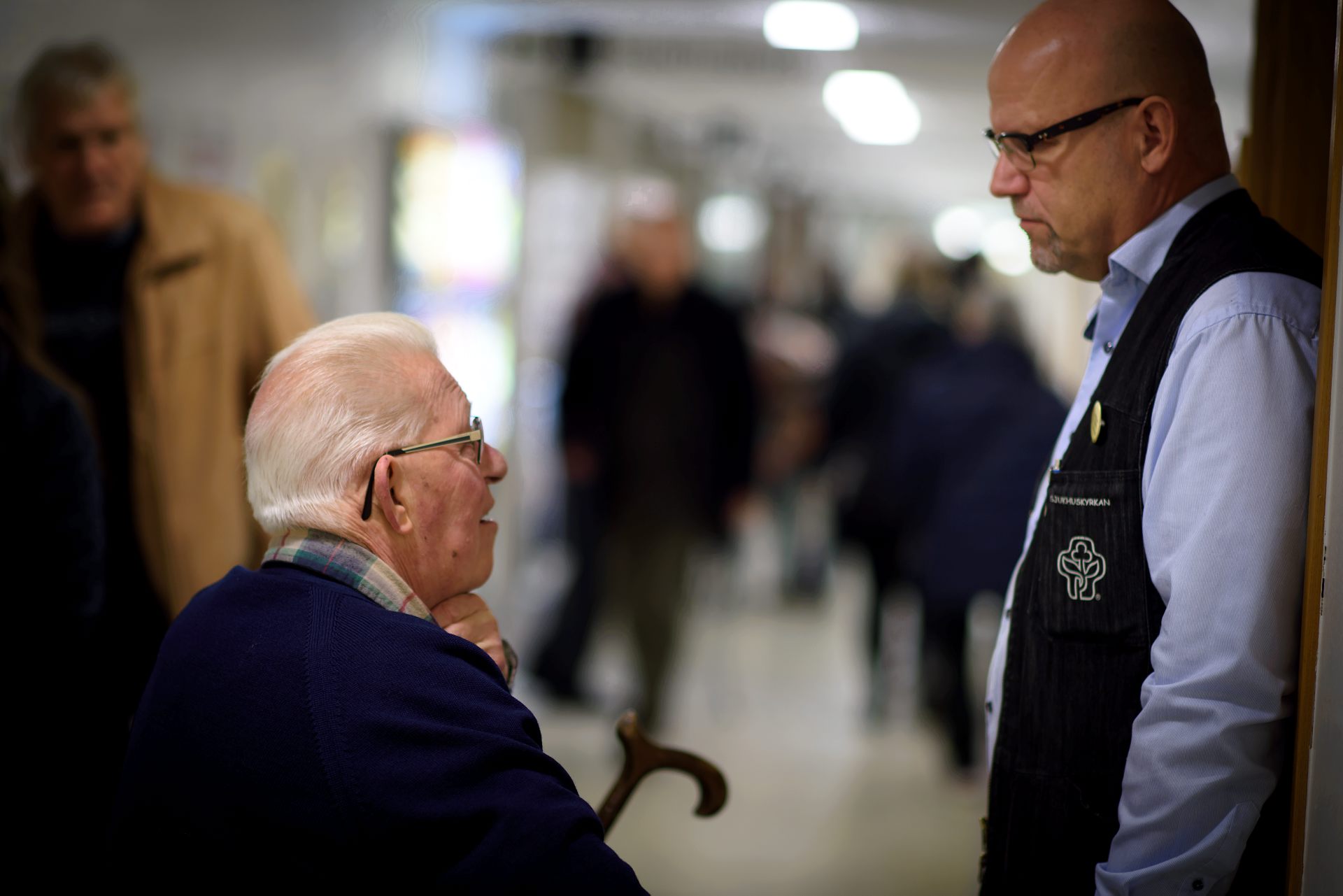En man som sitter samtalar med en man som står. 
