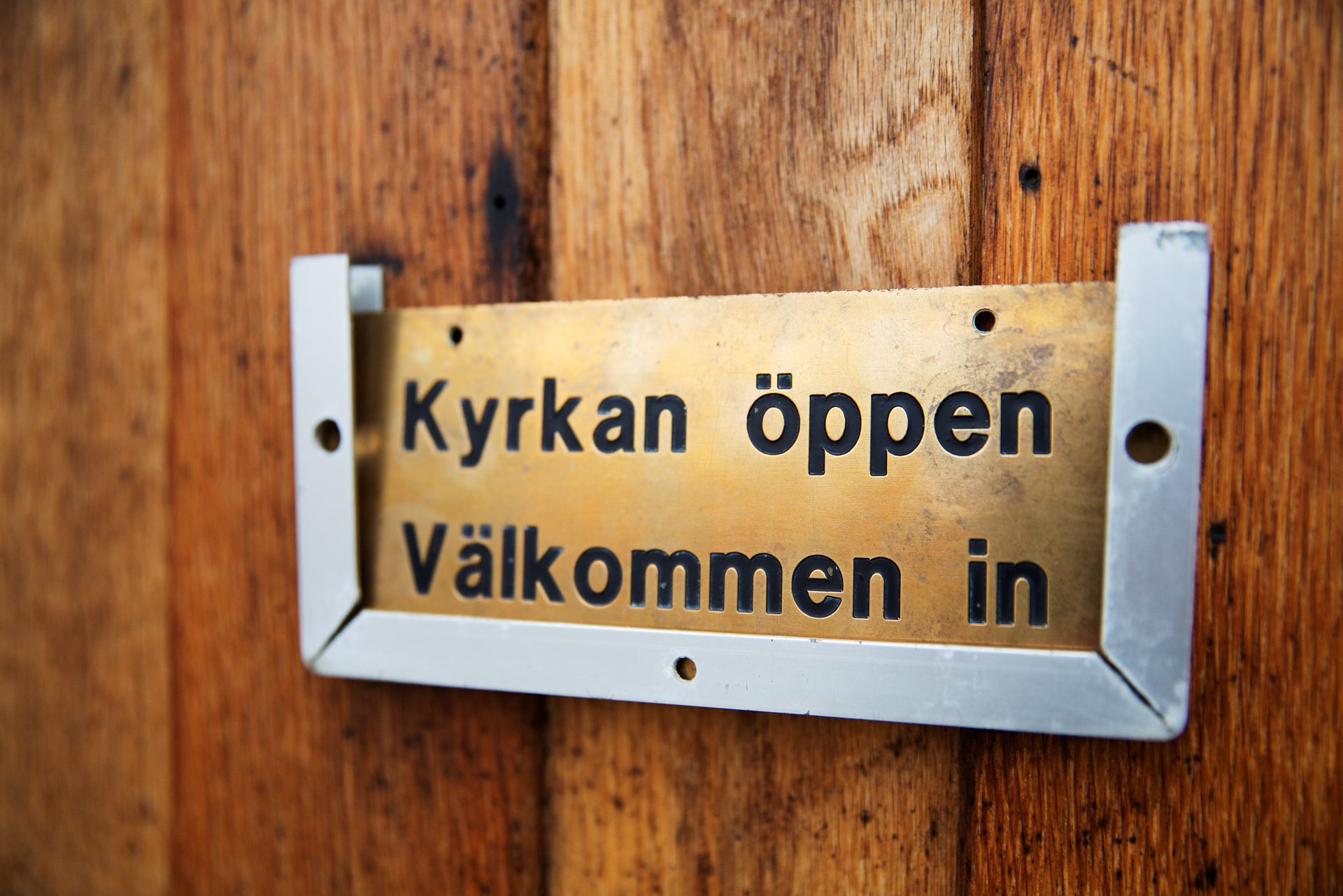 Dörrskylt med texten "Kyrkan öppen, välkommen in".
