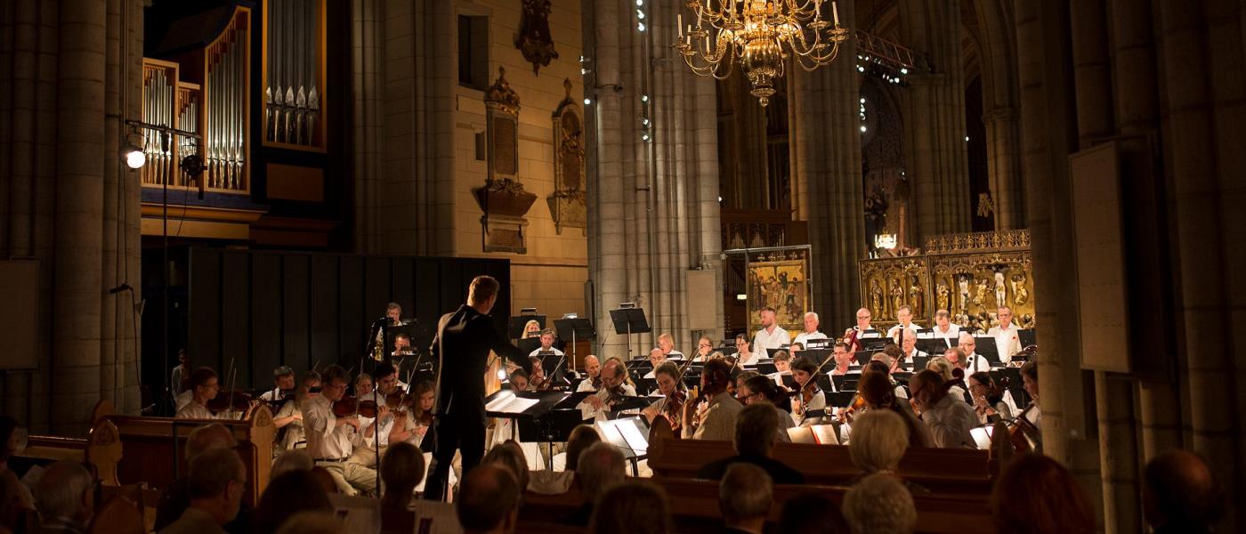 Orkester med dirigent spelar i kyrka.