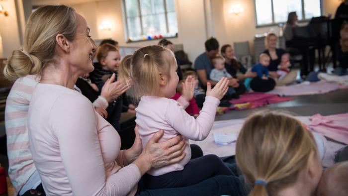 Barn och föräldrar sitter och skunger i en ring