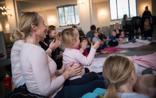 Barn och föräldrar sitter och skunger i en ring