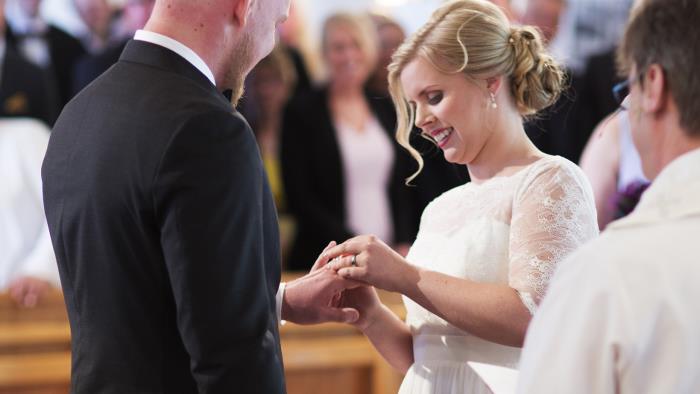 Bruden trär ringen på brudgummens finger.