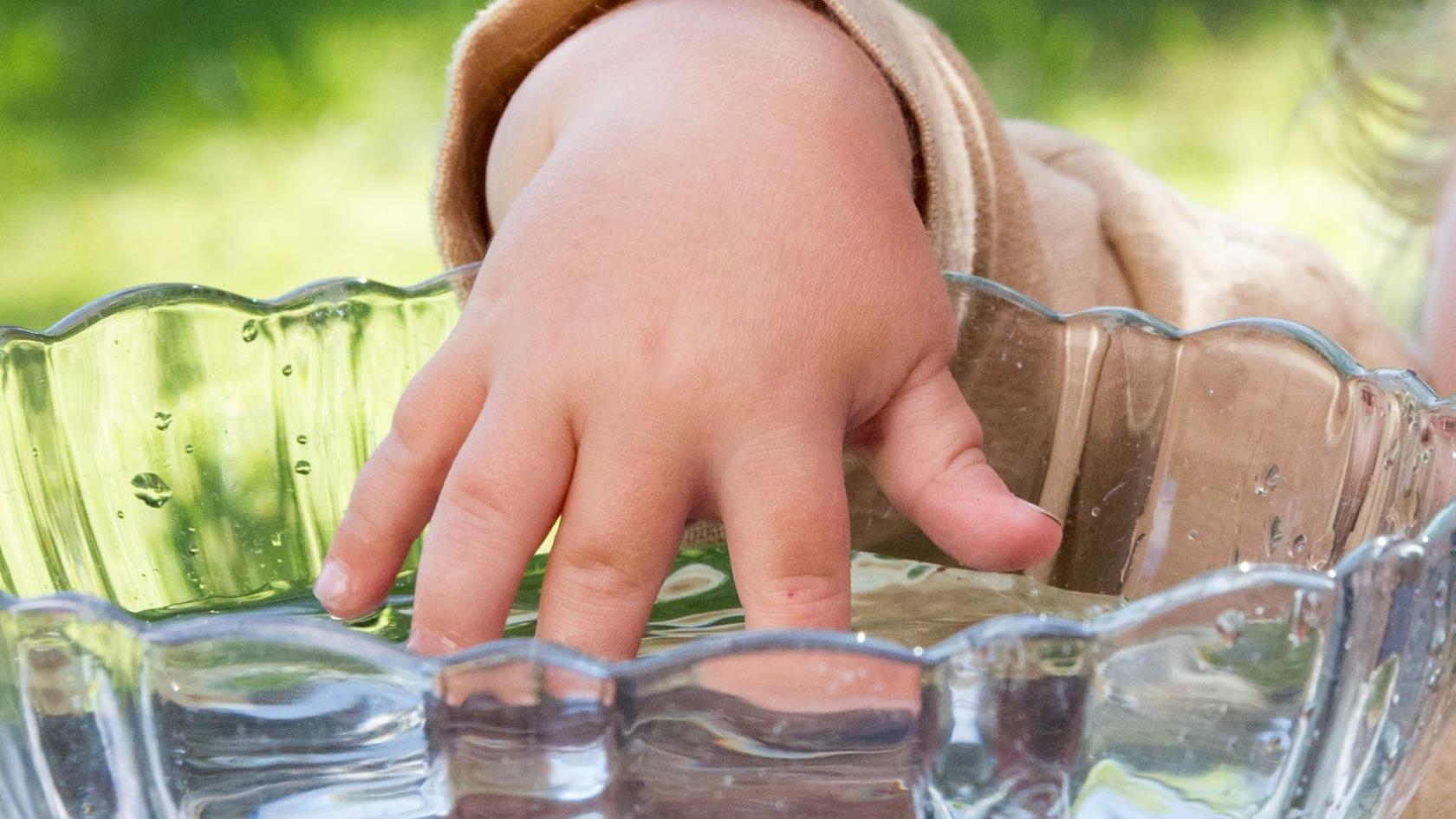 Ett barn doppar handen i dopkärlet