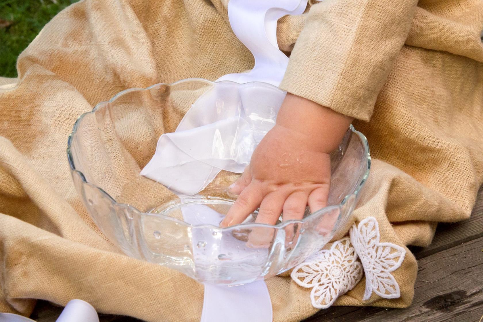 En barnhand i en skål med dopvatten