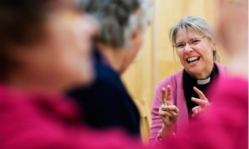 Glad präst i en grupp med vuxna
