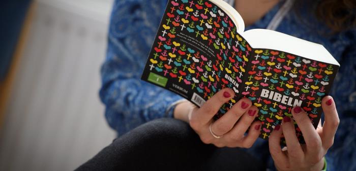 En person läser en bibel med färggrant omslag