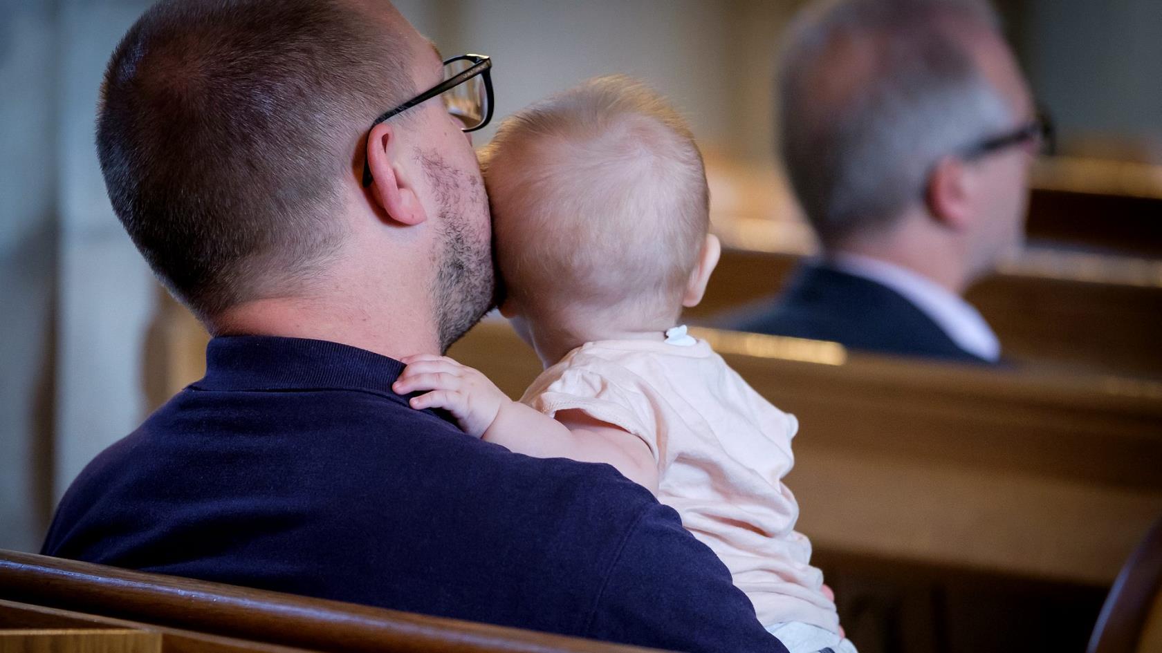 Pappa och barn sitter i kyrkbänken