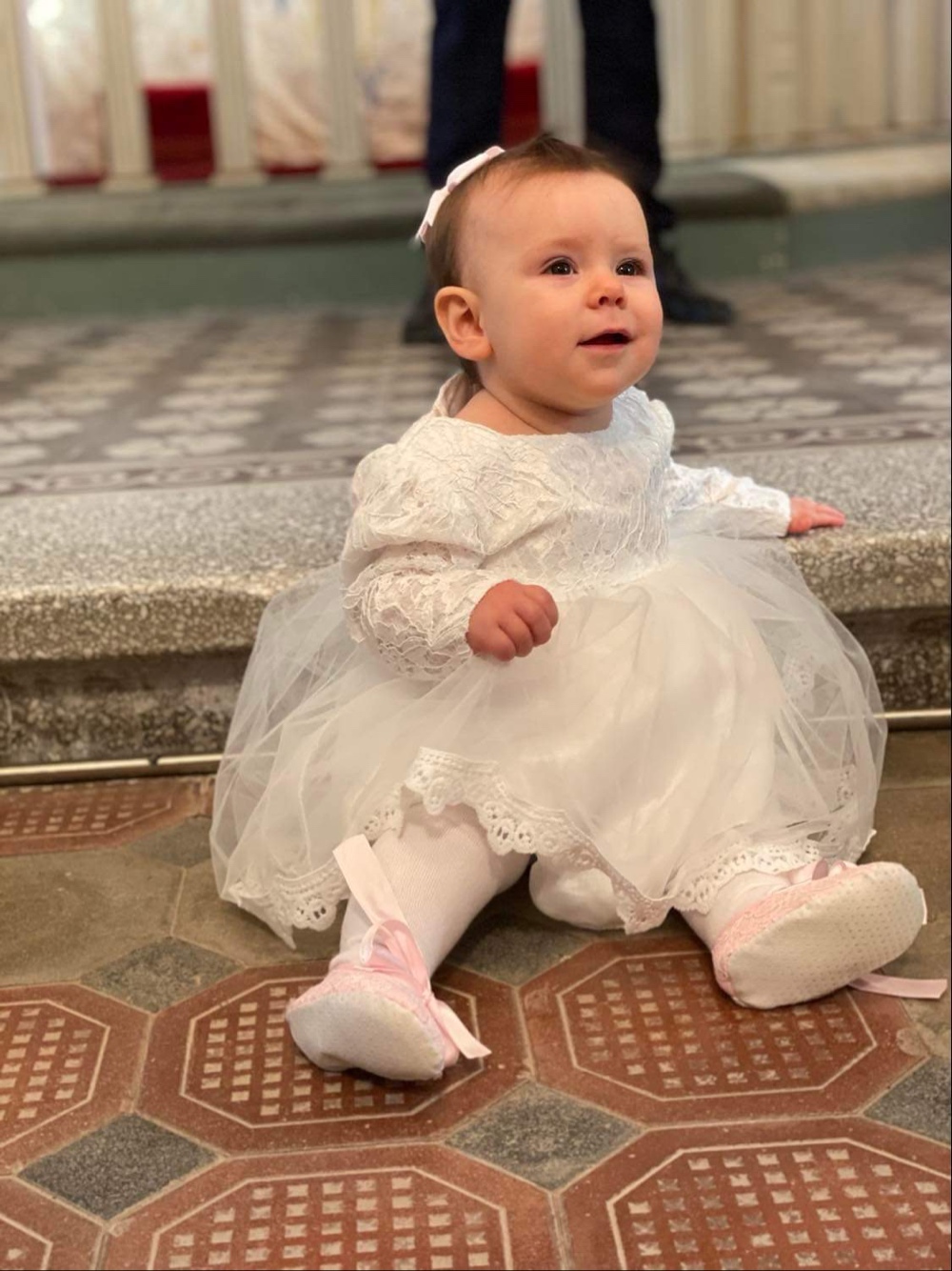 Flicka i vit klänning sitter på golvet i kyrkan.