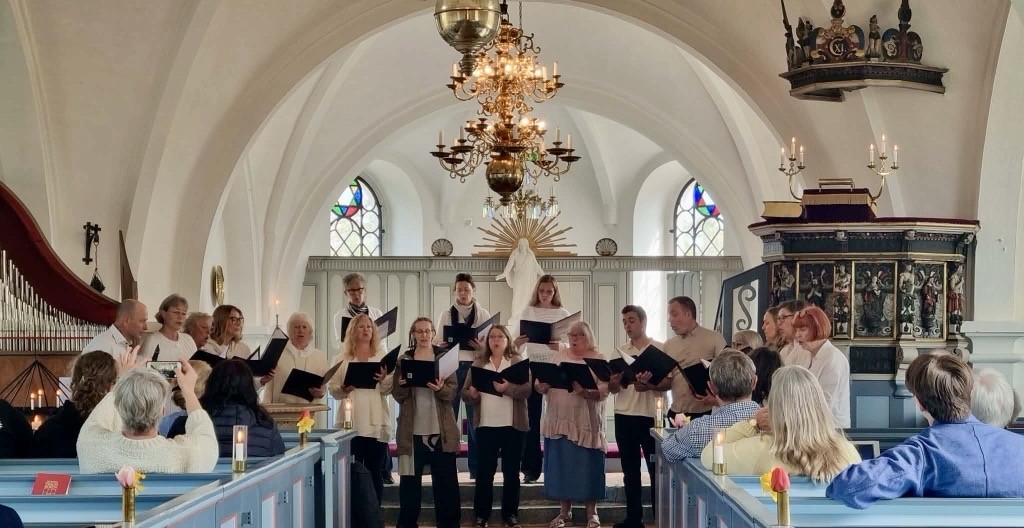 En kör står och sjunger i koret i en kyrka.