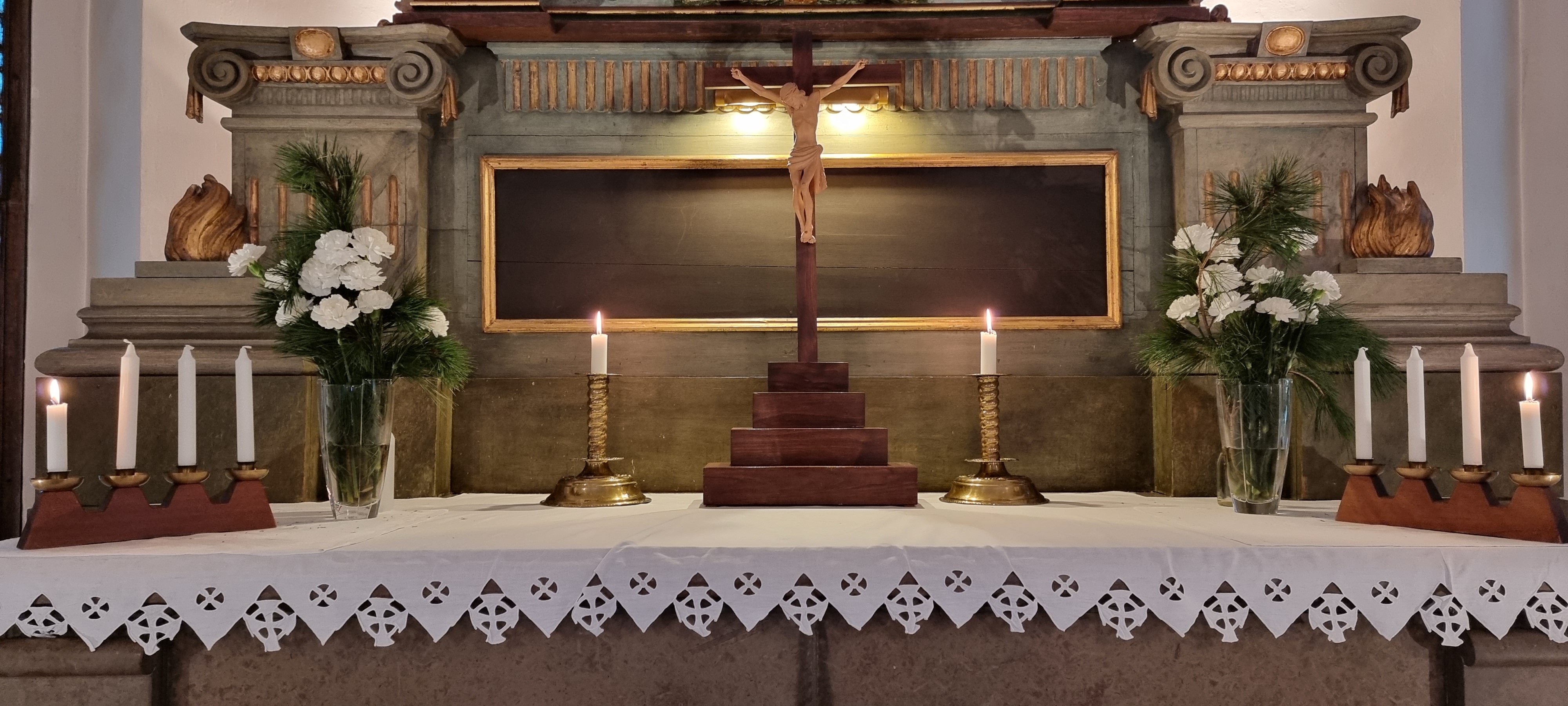 Ett altare med två adventsljusstakar och två blomvaser