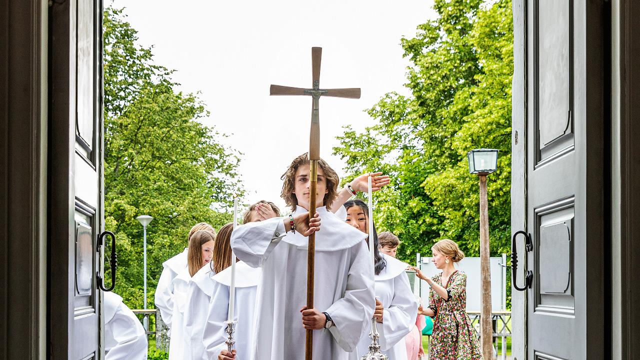 Konfirmander på väg att gå in i en kyrka i procession