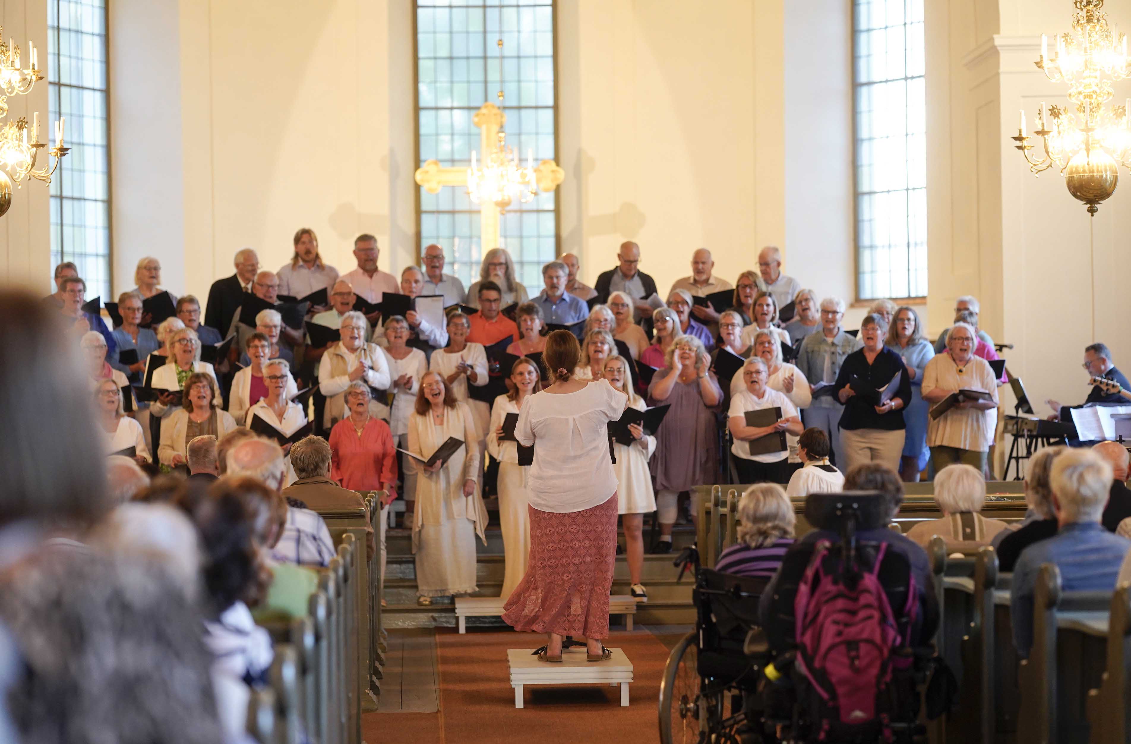 Körledare leder körsångare i Norra Vånga kyrka. 
