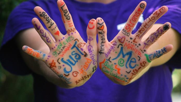 Två händer tecknade med färgpenna ord som beskriver personliga egenskaper.
