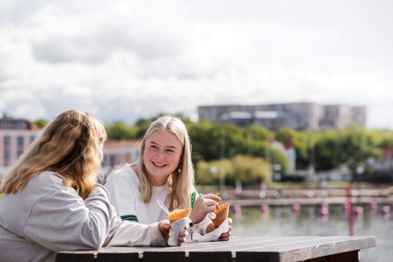 Två glada ungdomar som äter glass med slottsruin i bakgrunden