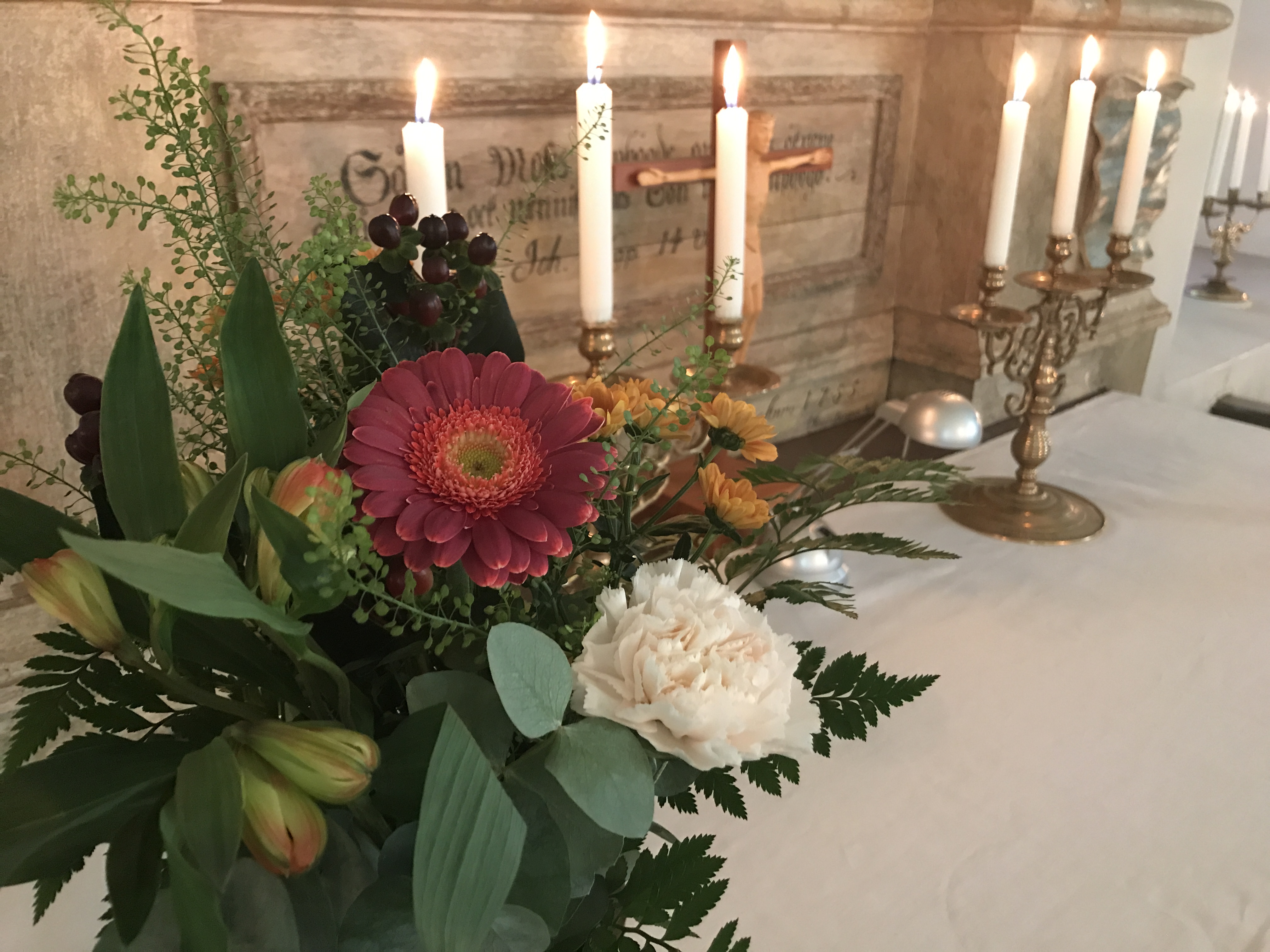 Höstblommor på altare med tända ljus
