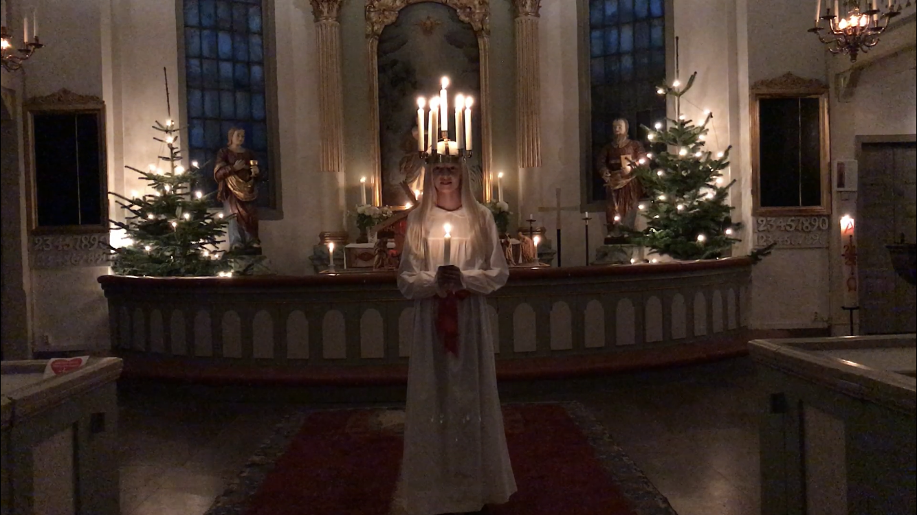 Lucia med tända ljus i håret och ljus i handen