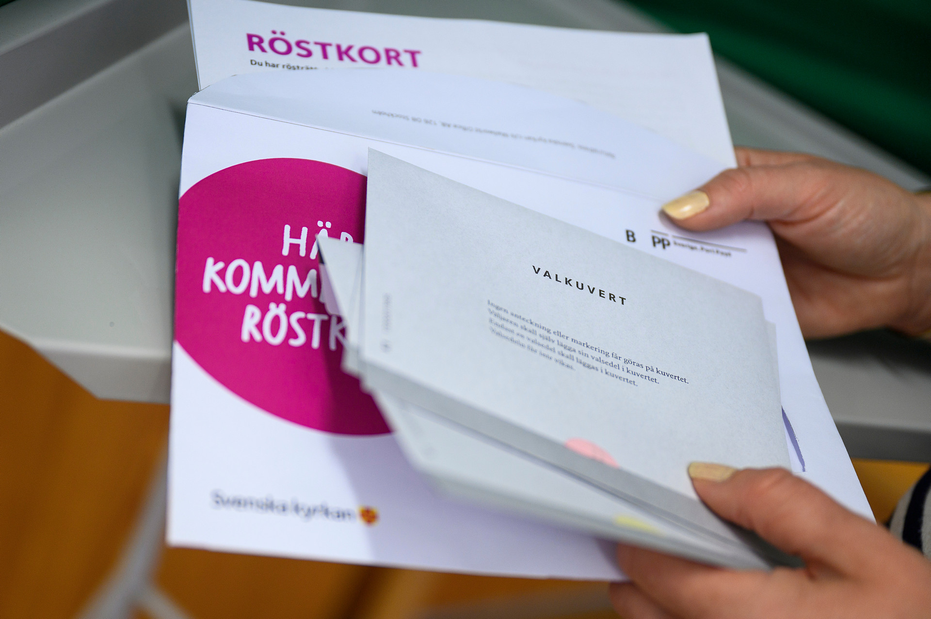 En hand som håller i ett vitt kuvert med "Valkuvert" tryckt på. 
