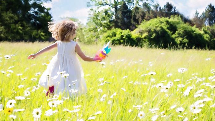 Ett barn som springer glatt på en blomsteräng.