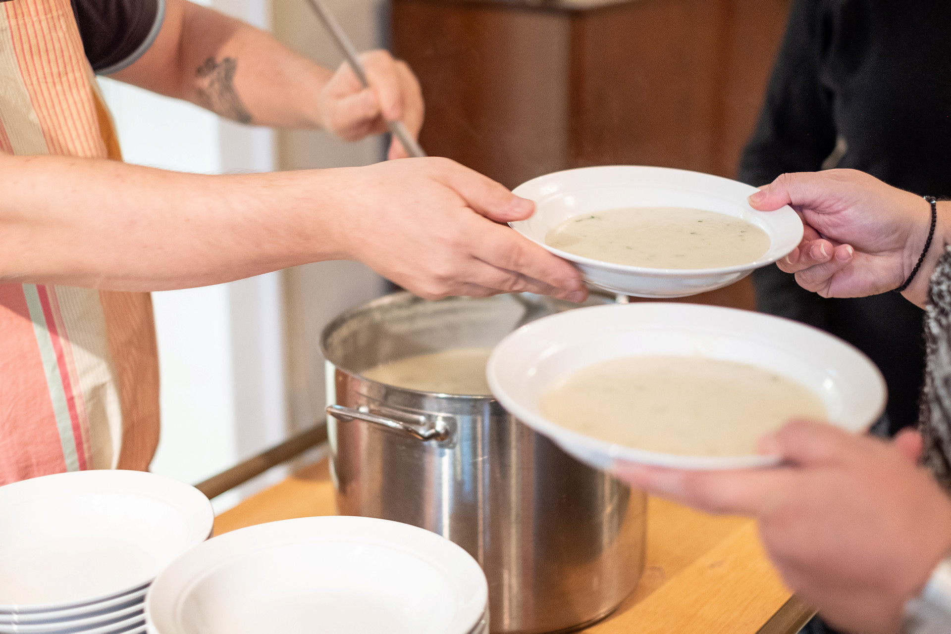 Person serverar soppa i djuptallrikar. 