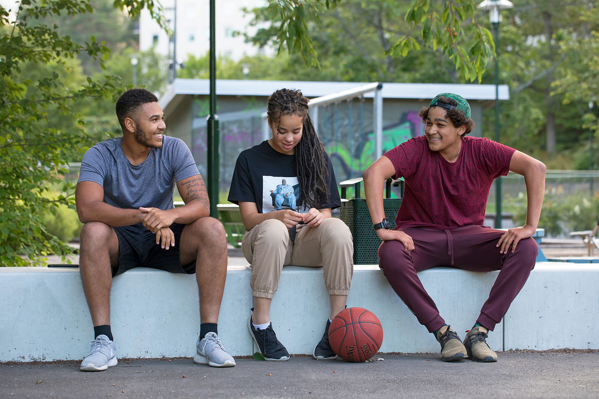 Tre ungdomar vilar sig en stund från basketspelandet.
