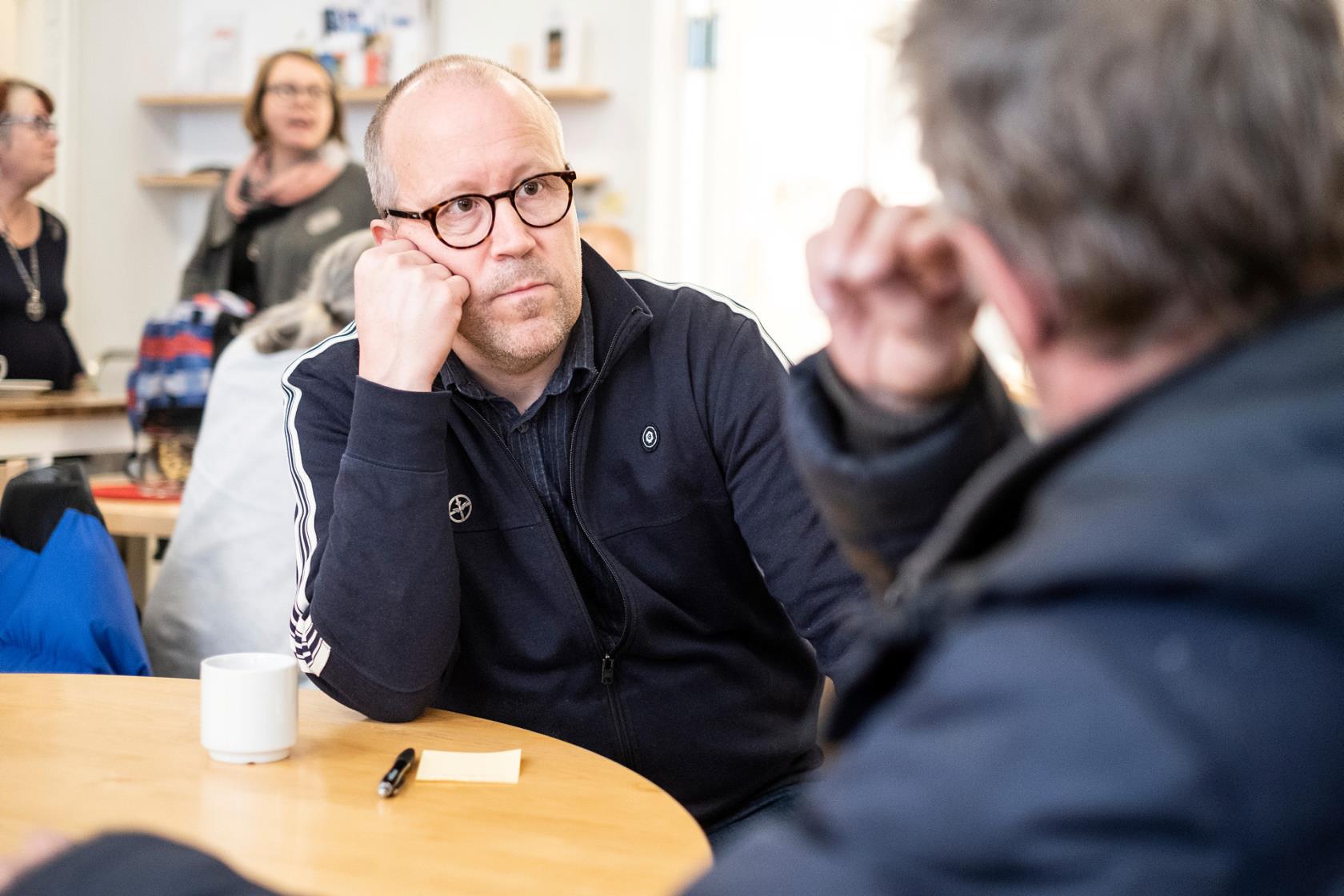 Två män i samtal över en kopp kaffe