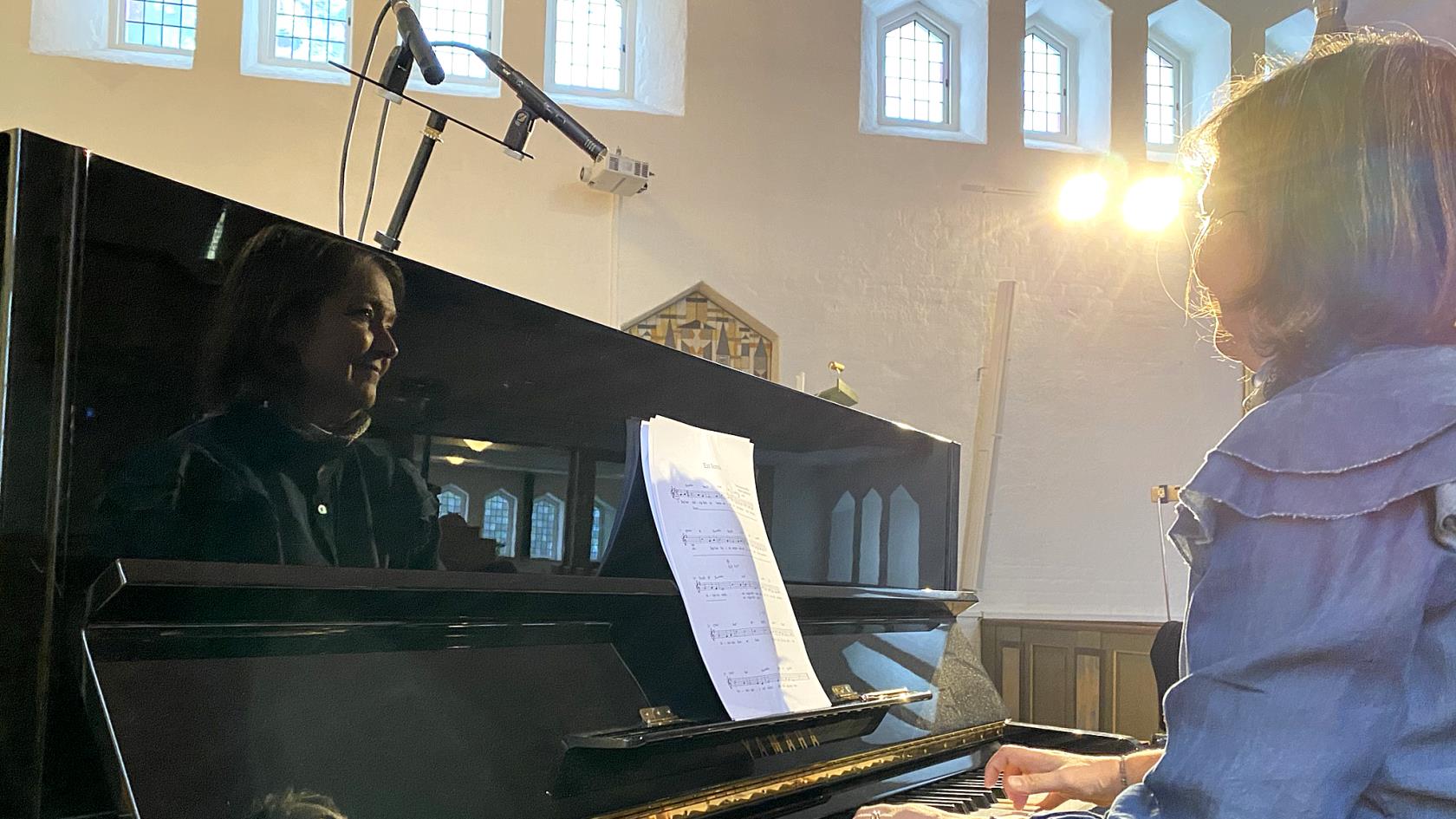 Musiker spelar piano och reflekteras i instumentet