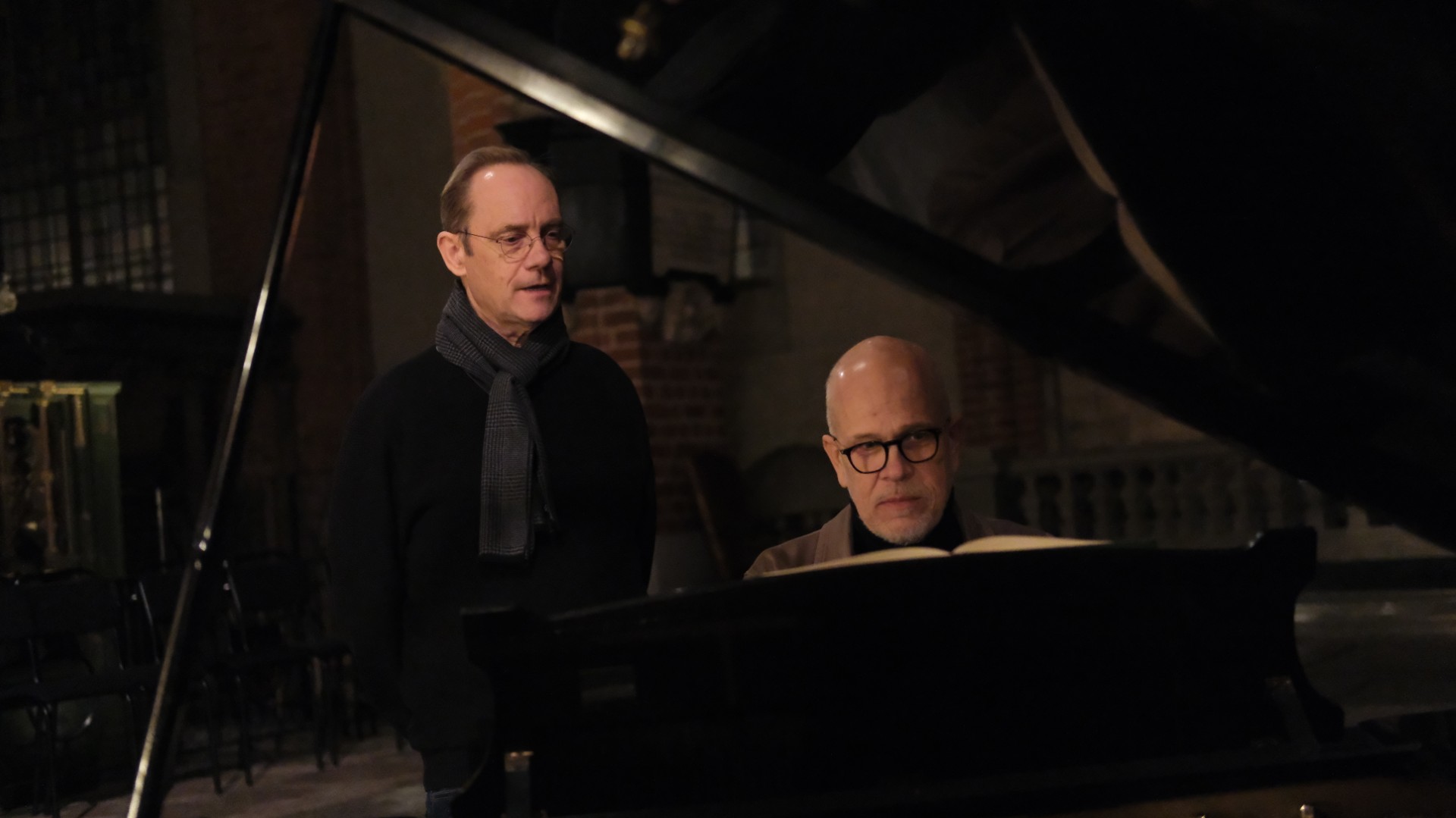 Två män bredvid varandra bakom en flygel, en spelar piano och en sjunger.