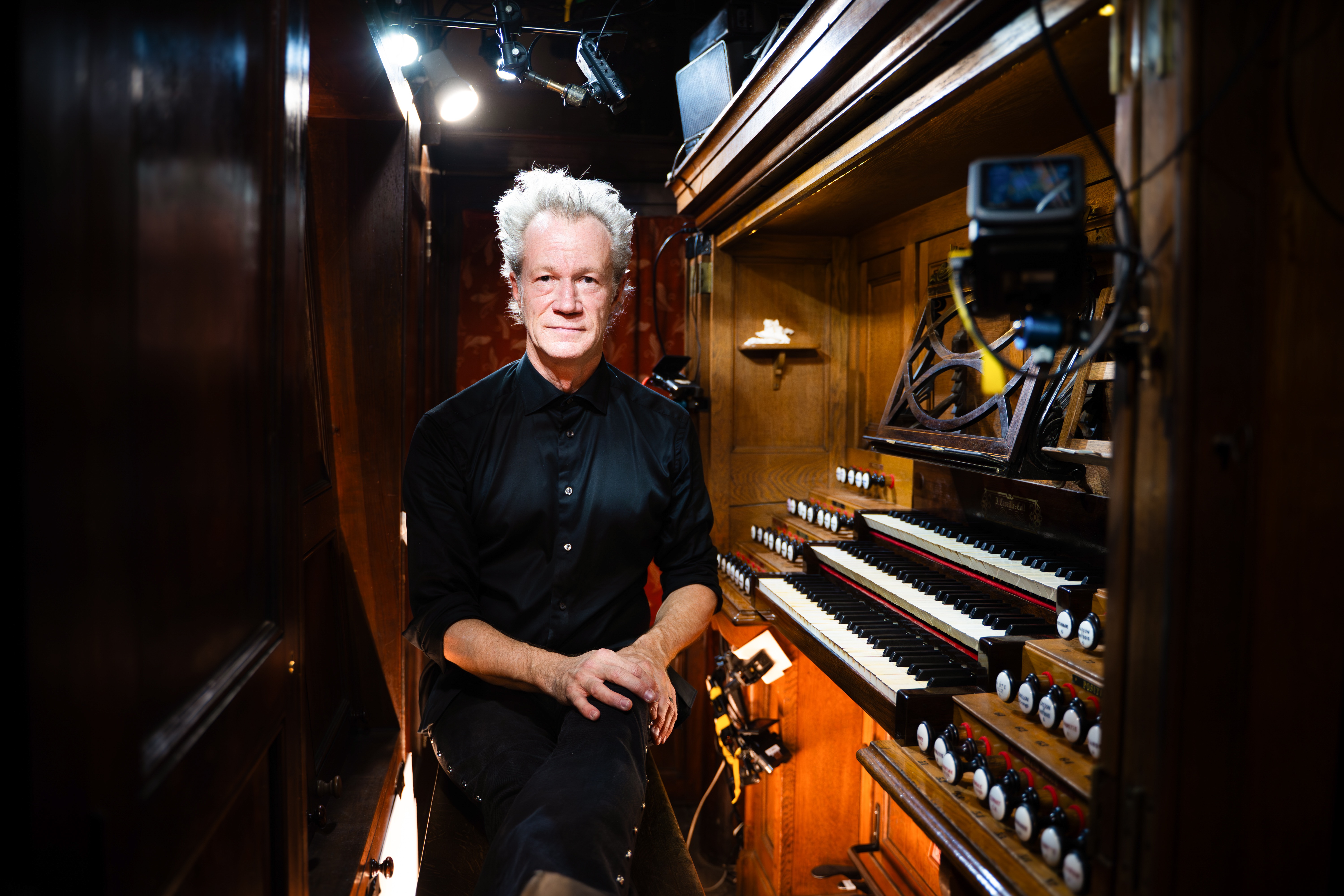 En man med vitt hår sitter vid en orgel.