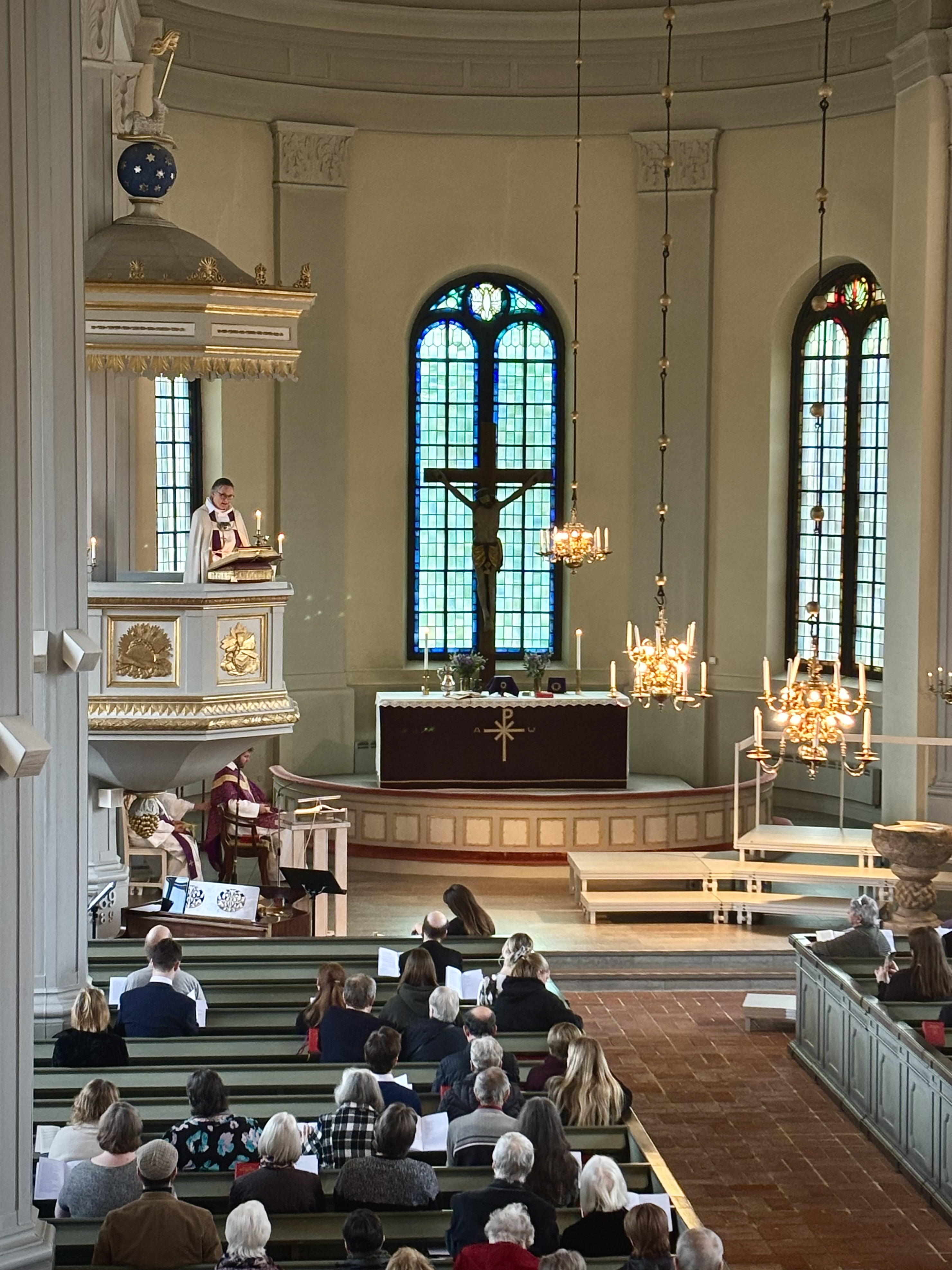 En kvinnlig biskop står i predikstolen i Västlands kyrka och talar till församlingsborna.