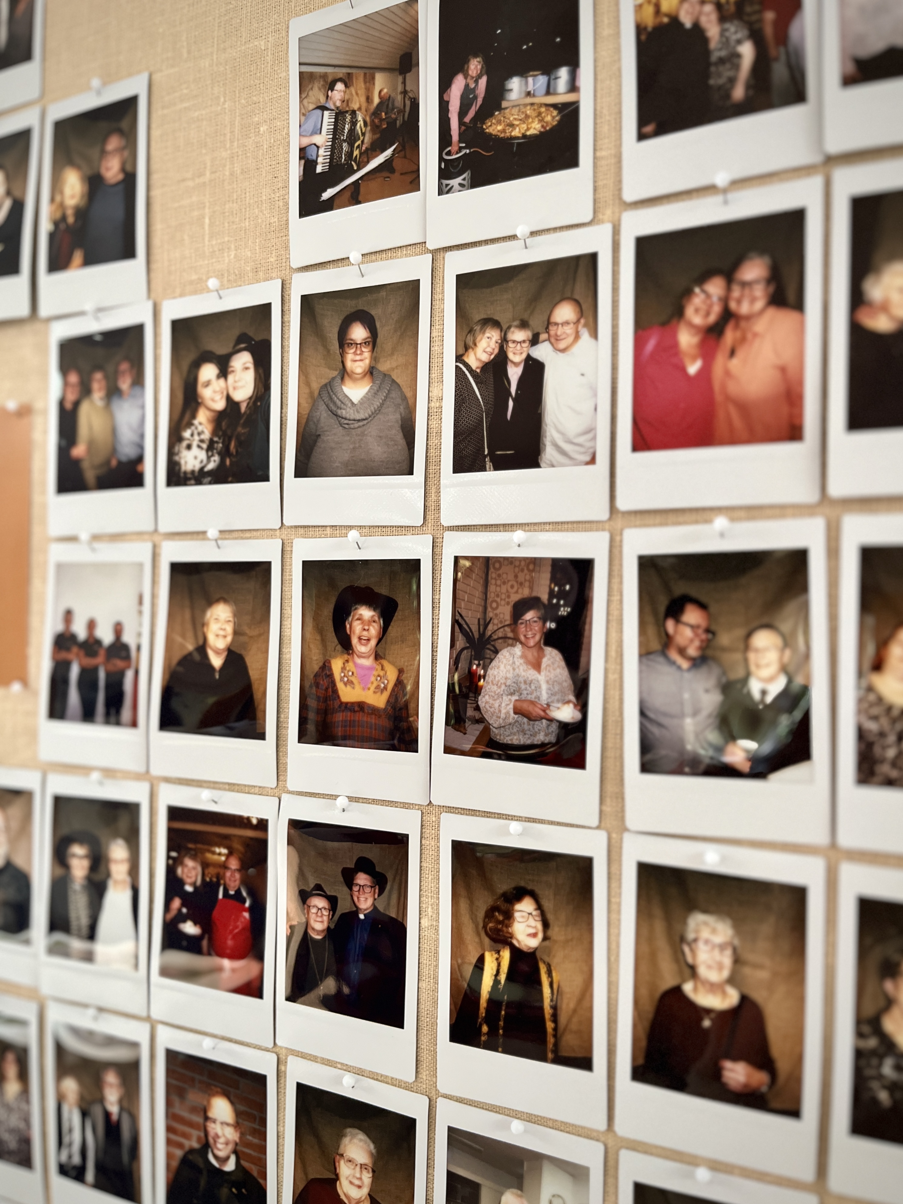 Bildkollage på en vägg med polaroidbilder av volontärer i ett pastorat.