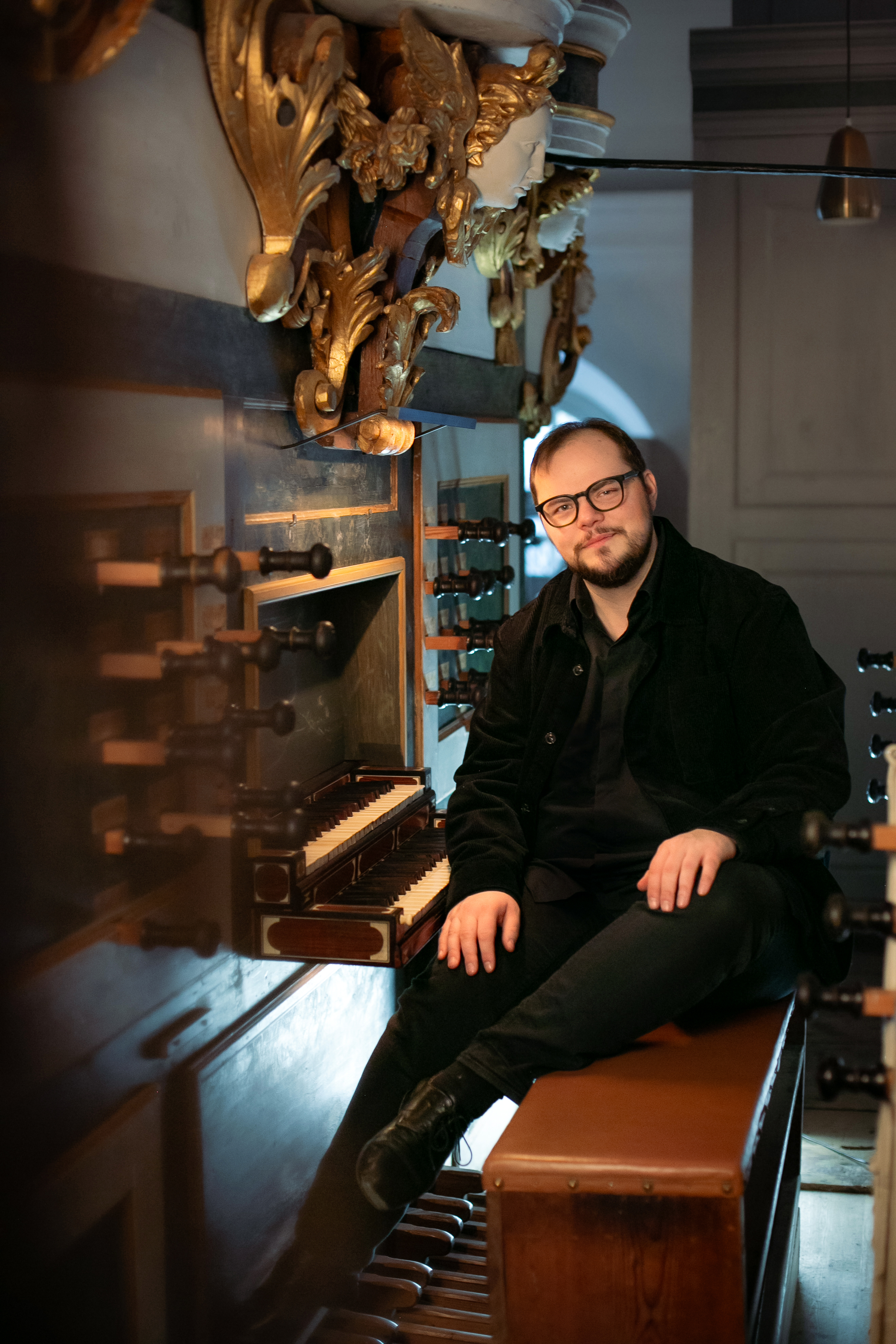 En manlig organist sitter på orgelpallen till Cahmanorgeln i Lövstabruks kyrka.