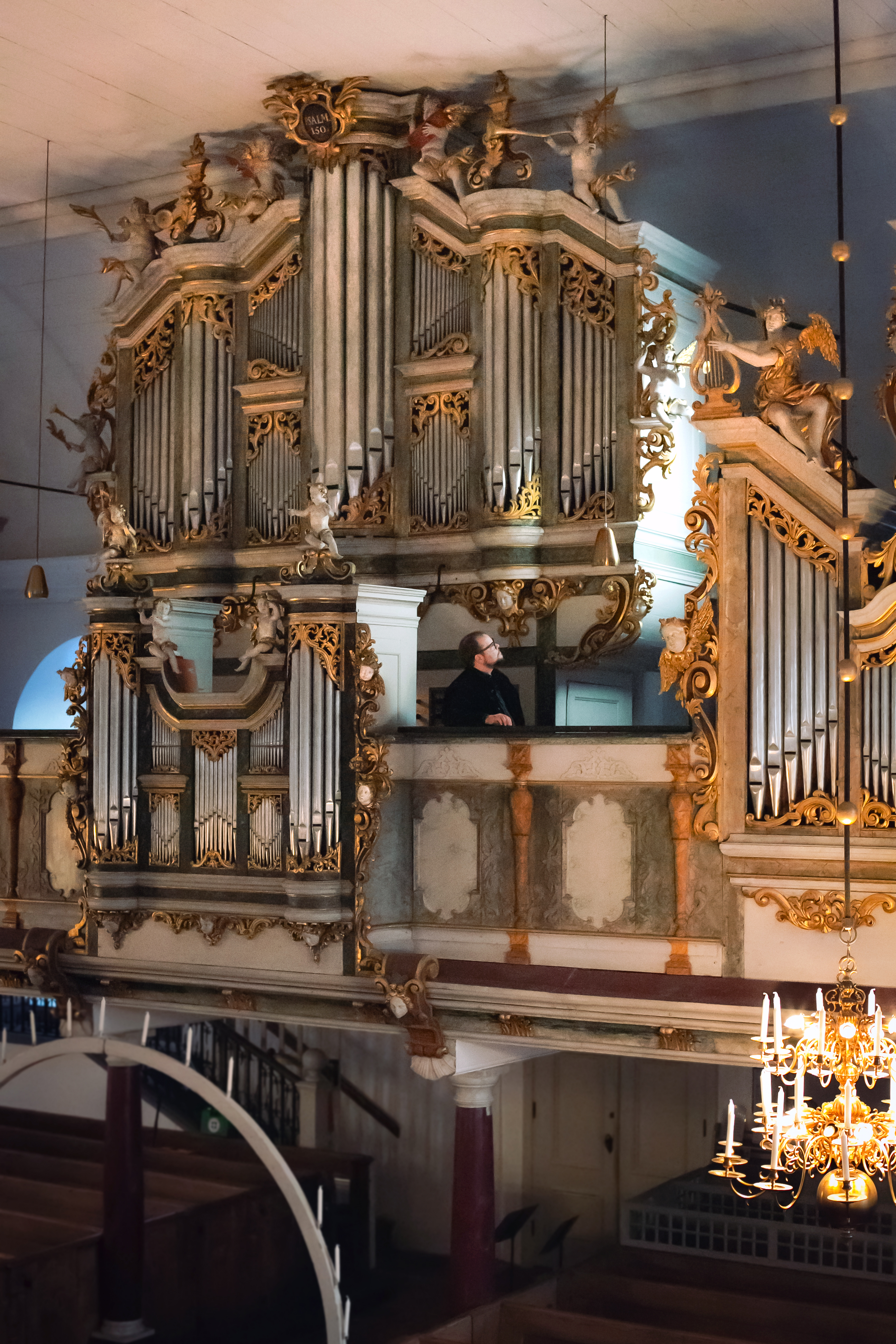 Cahmanorgelns fasad med en svartklädd man som står på orgelläktaren.