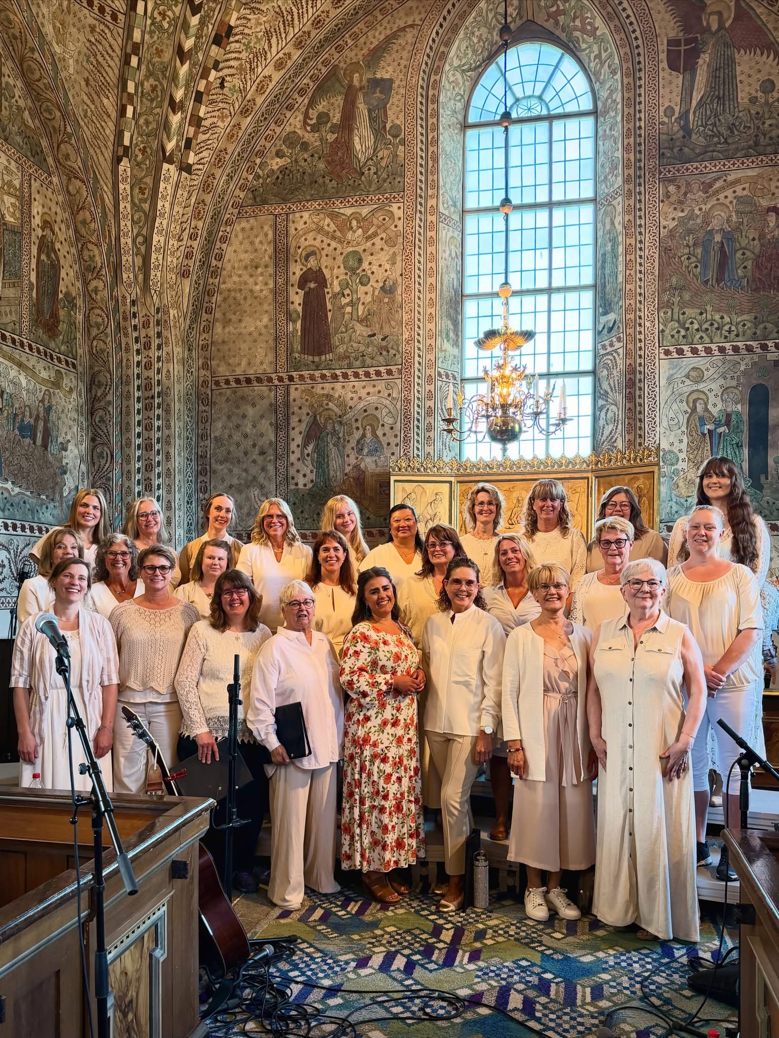 En damkör står uppställda i sommarkläder i Tolfta kyrka.
