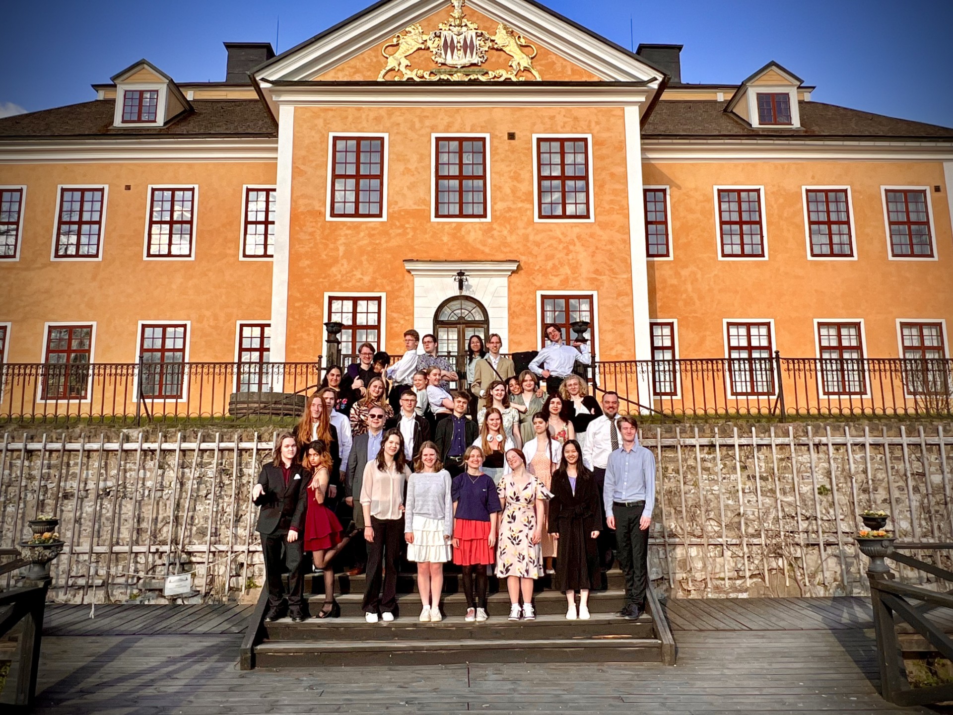 En grupp ungdomar, elever från ett musikaliskt gymnasium, står framför Lövstabruks herrgård.