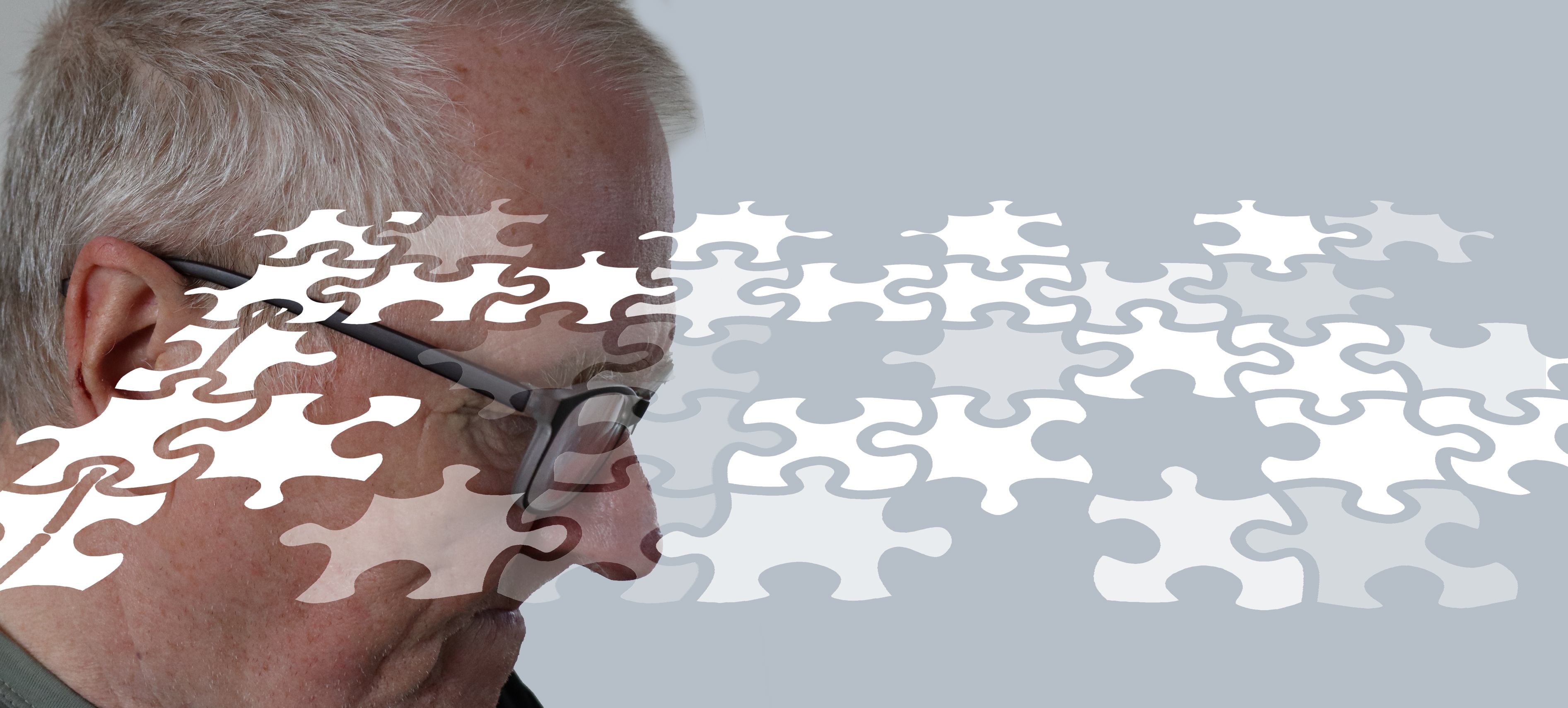 En man med demens sitter och grubblar, med pusselbitar som svävar framför honom.
