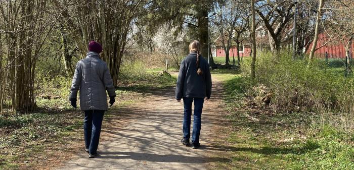 Två personer promenerar under samtal.