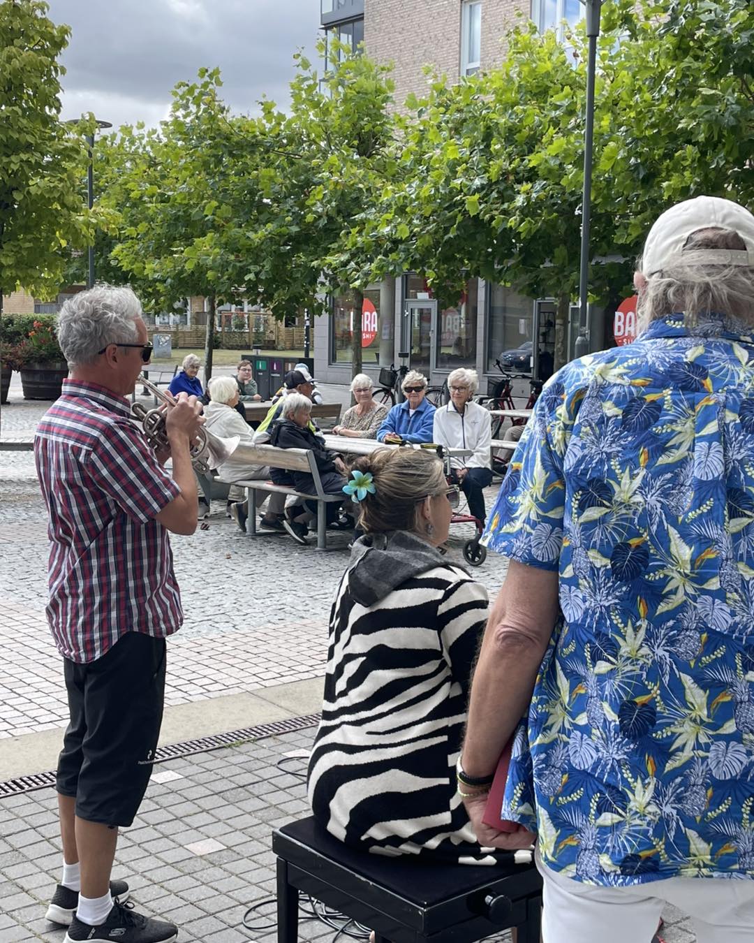 En man spelar trumpet, andra människor omkring.